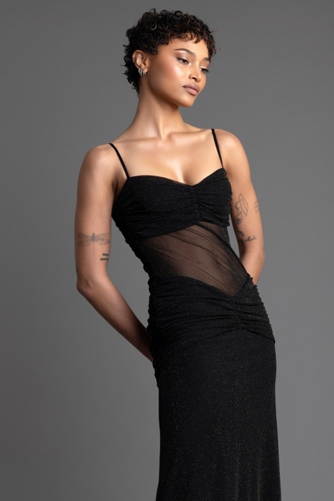 model wearing a black sparkling maxi dress with spaghetti straps and sheer mesh panels