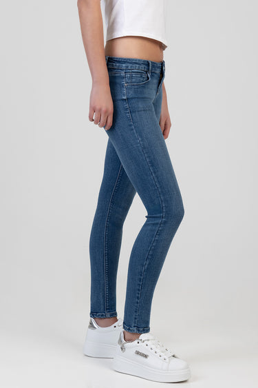 blue skinny jeans with a low rise on a model, visible front pockets, button and zip closure, paired with white sneakers