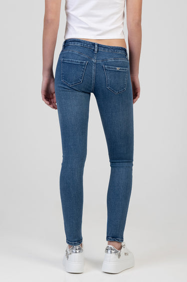 rear view of a person wearing blue low-waist skinny jeans and a white cropped top, white sneakers