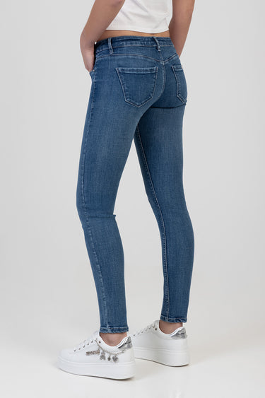 back view of a model wearing blue skinny jeans from Blue Jean Traders with white sneakers and a white crop top