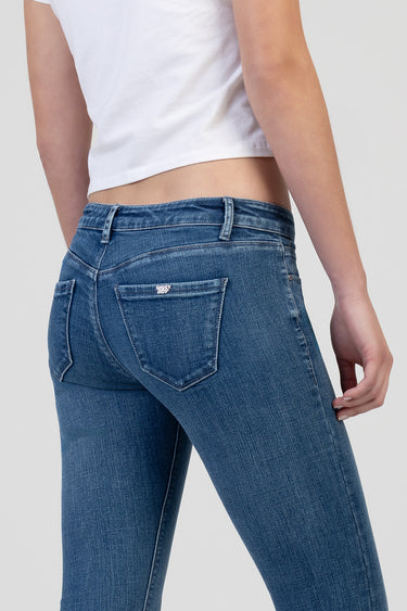 back view of a person wearing blue wash skinny jeans with a small brand badge on the back pocket