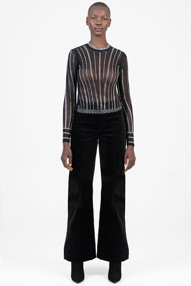 model wearing a sheer black long sleeve top with white vertical stripe pattern and wide leg black pants