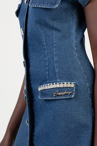 close up of blue denim dress showing a rhinestone trimmed pocket and silver buttons along the front