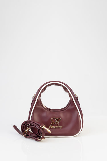 maroon mini bag with white piping, gold emblem and a detachable strap against a white background