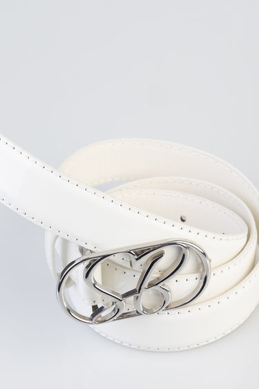 white patent belt by blue jean traders with a silver buckle, coiled on a light background