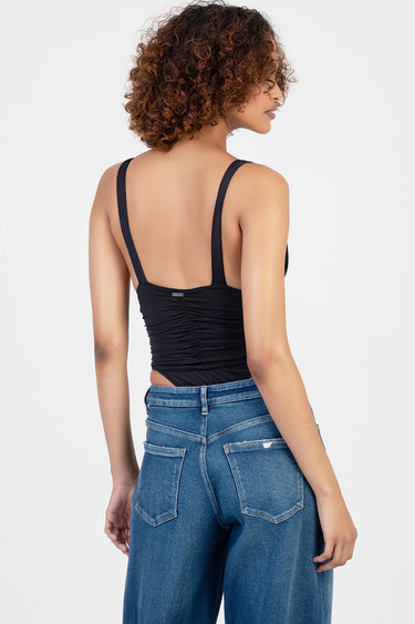 back view of woman in black ruched sleeveless bodysuit with wide straps paired with blue denim jeans