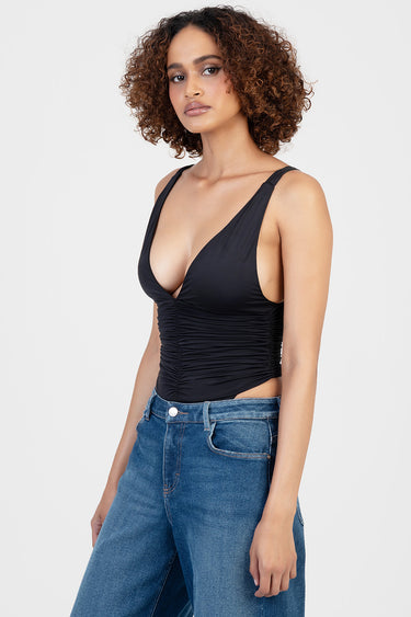 woman wearing black ruched front bodysuit with a deep v neckline and wide straps, paired with blue jeans