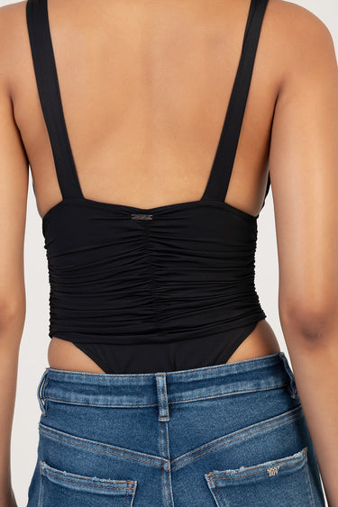 back view of a black ruched bodysuit with wide straps, paired with blue denim jeans