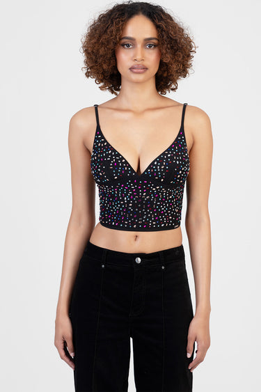 woman wearing a black cropped top with multicolour sequin specks, v neckline and thin straps, paired with black jeans