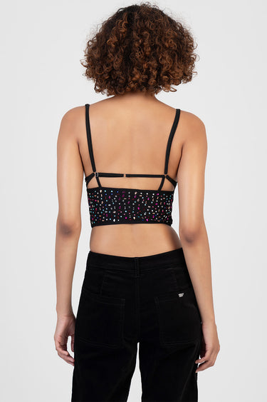 back view of a black beaded crop top with adjustable straps and a slim back band, worn with black pants