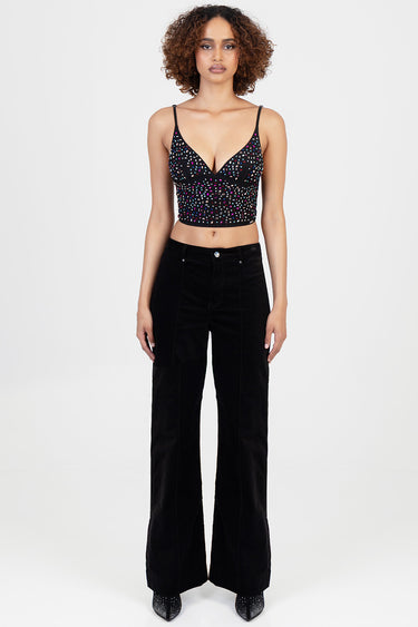 woman wearing a black cropped top with multicolour speckles and high waisted wide leg black trousers