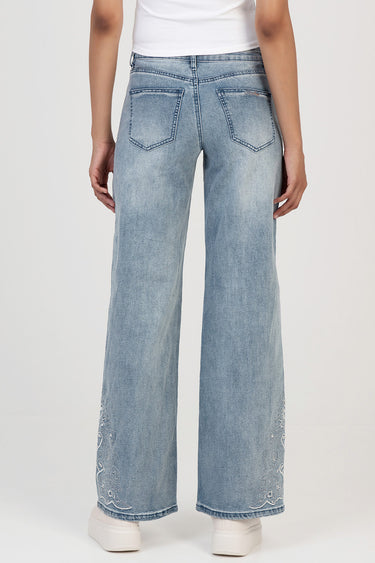 back view of light wash wide leg jeans with two back pockets and paisley embroidery at the lower legs, paired with white