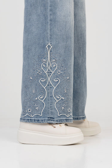 blue wide leg jeans with white embroidered paisley detailing at the hem, shown with beige platform sneakers