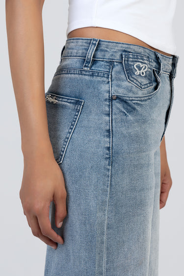 woman wearing light wash wide leg jeans with back pocket embroidery and belt loops, white cropped top