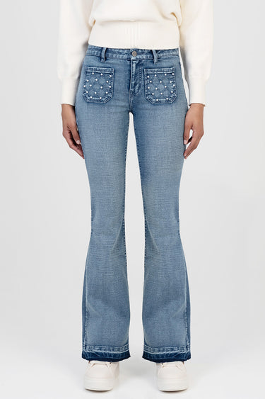 woman wearing light blue denim jeans with quilted back pockets decorated with pearls and a wide flare at the bottom