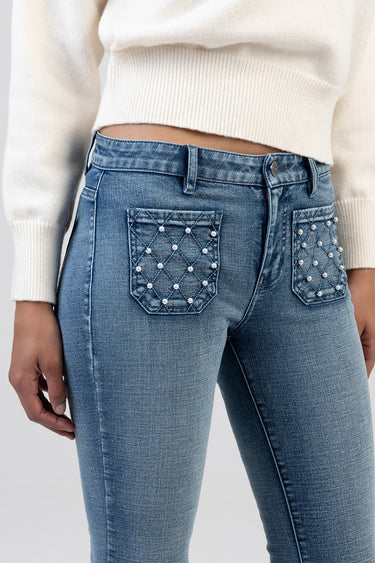 woman wearing light blue jeans with pearl studs on the back pockets; left pocket has a quilted diamond pattern, paired with