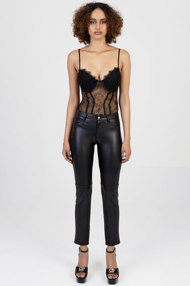 model wearing a black lace bodysuit with sheer panels and structured cups, paired with black faux leather jeans and