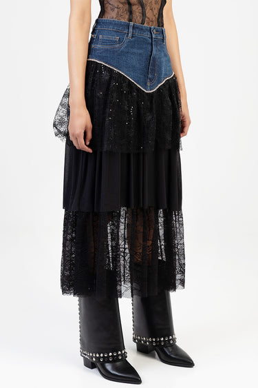 woman wearing a blue denim midi skirt with a chevron lace seam and black lace overlay over a tulle underlayer, paired with