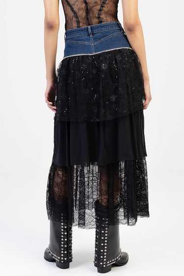 back view of a model wearing a blue jean traders denim waistband with a layered black lace midi skirt and studded black boots