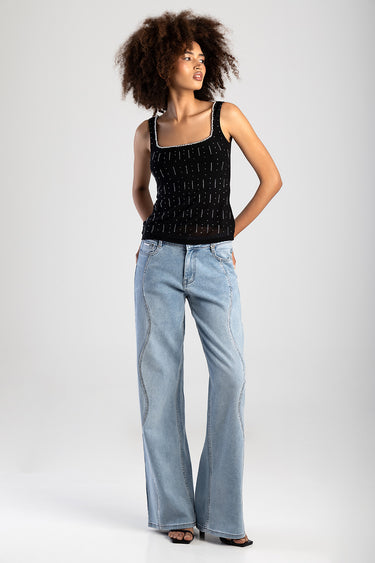 woman wearing black knit top with white bead trim and light wash wide leg jeans by Blue Jean Traders