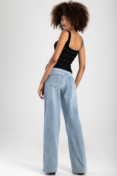 woman with curly hair in black knit top with silver studs, back view, light wash wide leg jeans