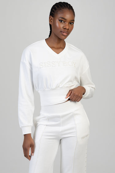 woman in a white cropped sweatshirt with rhinestone lettering across the chest and matching high waisted white pants with