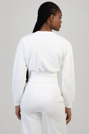 woman wearing a white cropped sweat top with long sleeves and matching high waisted pants, back view, braided hair