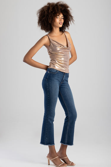 woman wearing a rose gold metallic tank top with a draped neckline and blue cropped flare jeans with beige heeled sandals