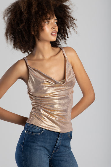 woman wearing a metallic rose gold sleeveless top with ruched detailing and a v-neck, paired with blue jeans