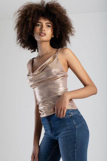 model wearing metallic gold sleeveless top with a draped neckline and blue denim jeans