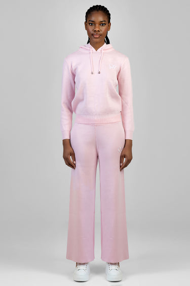 woman wearing a light pink knit hoodie with drawstrings and matching wide leg pants in a pink gradient, with white sneakers