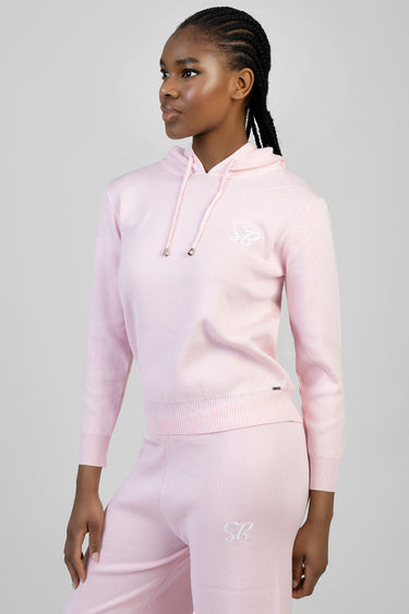woman wearing a pastel pink knit hoodie with drawstrings and ribbed cuffs, paired with matching pink jogger pants with a