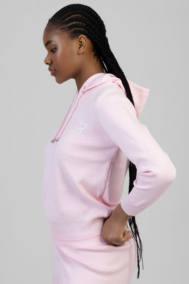 side profile of a woman in a pale pink knit hoodie with drawstrings and a small logo on the chest