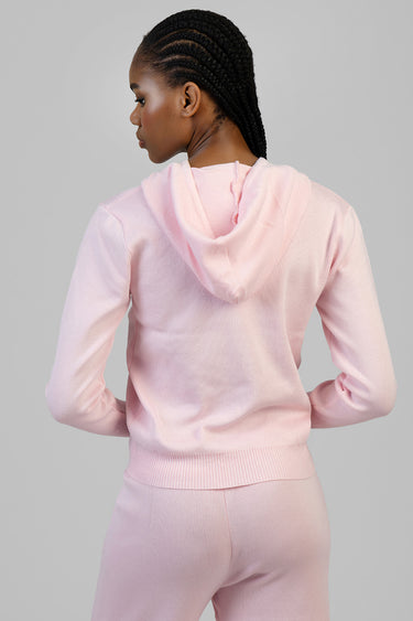woman in pale pink knit hoodie with hood and ribbed hem, back view with braided hair against neutral backdrop