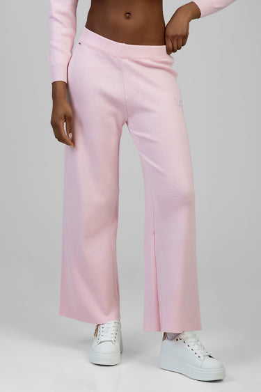 woman in light pink knit wide leg pants with a small logo on the thigh and white sneakers