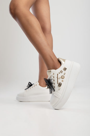 white platform sneaker with jeweled charms along the side and black lace bow laces