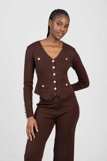 woman in a brown ribbed knit cardigan and matching trousers with gold buttons and a v neck pocket flap design