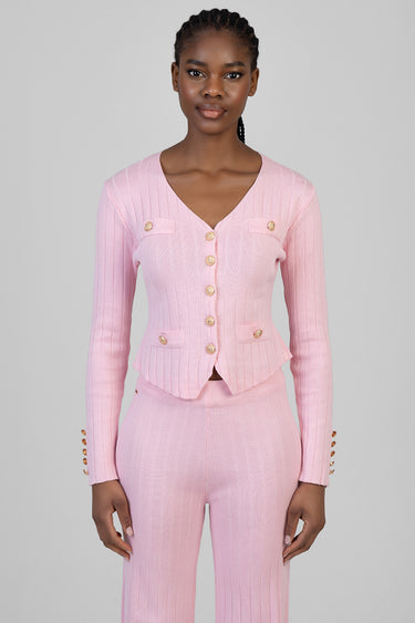 woman wearing a pink knit cardigan with gold buttons and matching knit pants; ribbed texture and v neck.