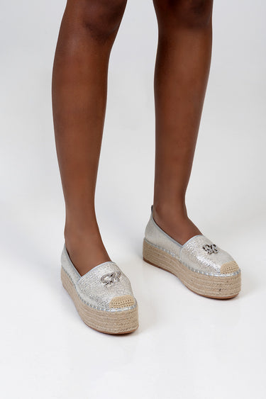 silver espadrille flats with woven rope sole, metallic upper, and decorative charms on the toes