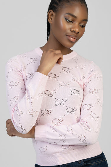 woman in a light pink knit top with an allover eyelet pattern and long sleeves, crew neck