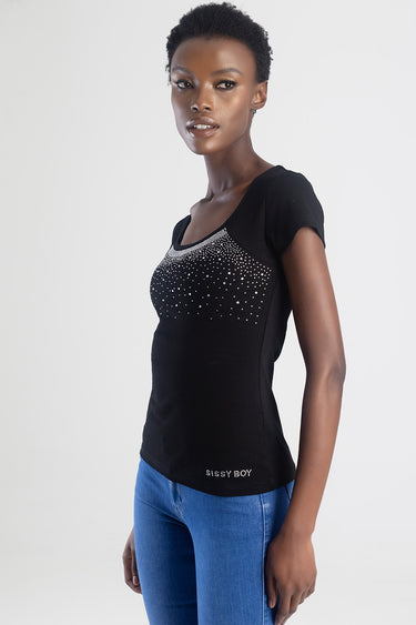woman wearing a black short sleeve top by Blue Jean Traders with rhinestone detail across the chest, paired with blue jeans