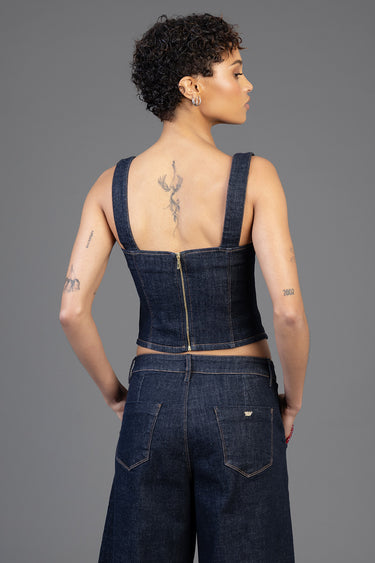 woman wearing dark blue denim crop top with wide straps and a gold zipper, back view, paired with high waist jeans