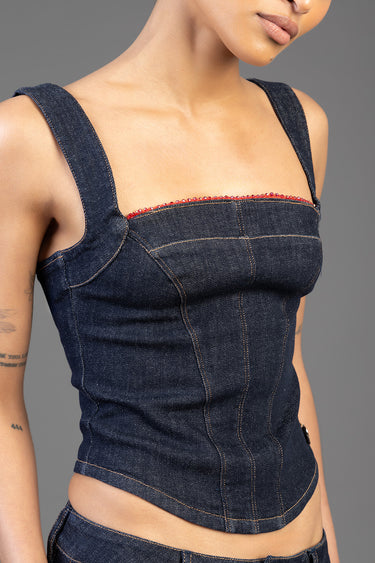 woman wearing dark wash denim top with wide straps and red beaded trim along the neckline