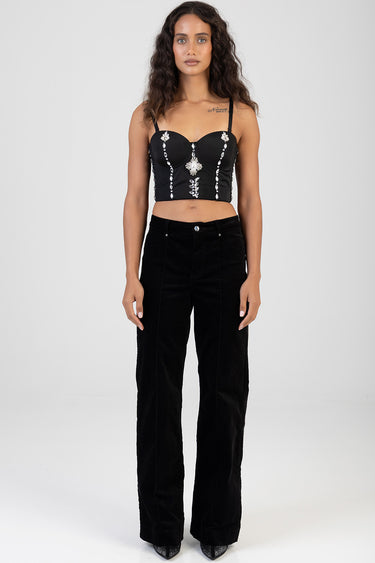 woman wearing a black corset top with crystal embellishments by Blue Jean Traders, paired with wide black trousers and