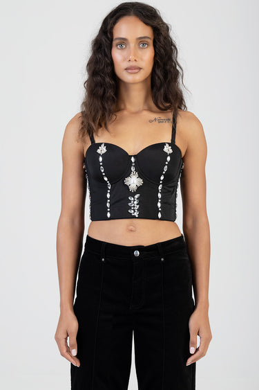 woman wearing a black embellished cropped top with crystal appliques and structured cups, paired with high waist black pants