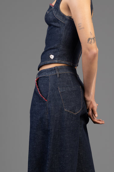 side view of a person in dark denim high waist wide leg jeans with a red beaded chain detail on the back pocket