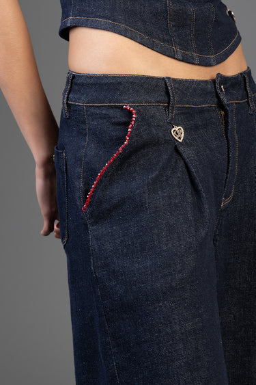 side view of blue jean traders wide leg jeans in dark indigo with red bead pocket trim and a heart charm