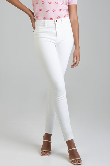 model wearing white skinny jeans from Blue Jean Traders paired with a pink patterned top and strappy sandals