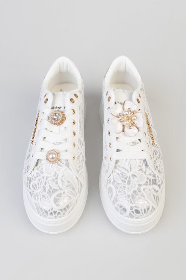 white lace sneakers with gold eyelets and jeweled floral pins on the laces