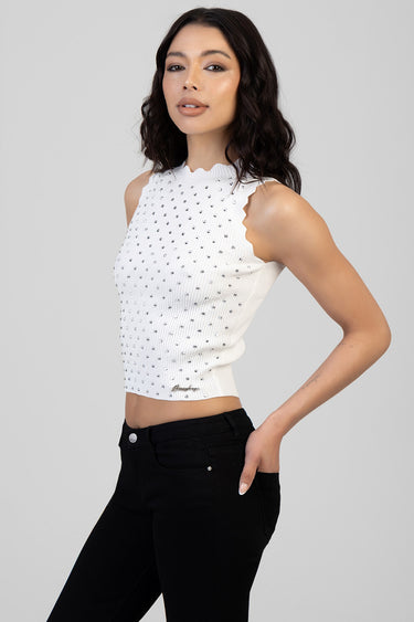 woman in white knit sleeveless top with scalloped edges and silver studs, worn with black jeans